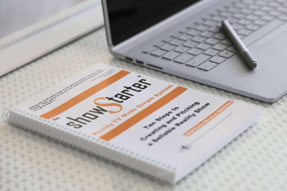 A book lies on a table next to a laptop computer