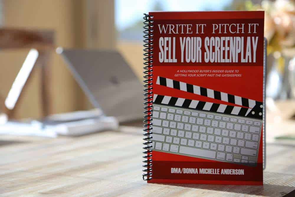 A book stands on a table with a laptop in the background.